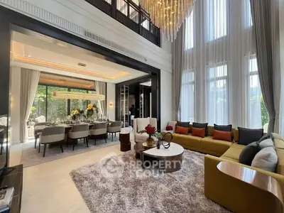 Luxurious living room with high ceilings, elegant chandelier, and spacious dining area.