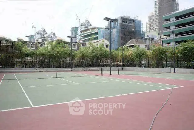 Spacious tennis court in urban residential complex with city skyline view