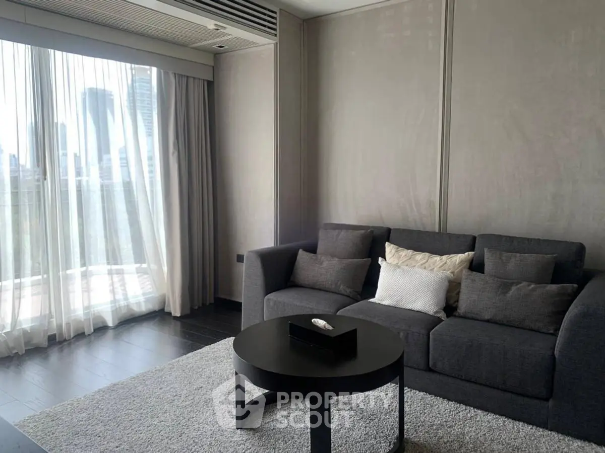 Modern living room with stylish gray sofa and city view through large windows.