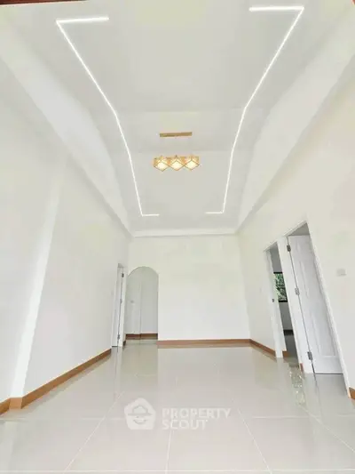 Spacious modern living room with elegant ceiling lights and glossy tiled flooring.