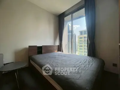 Modern bedroom with large window offering stunning city view in high-rise apartment.