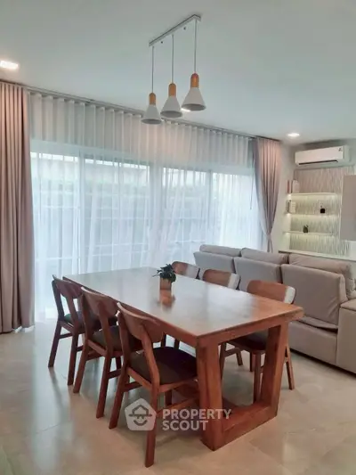 Modern dining area with wooden table and chairs, elegant lighting, and large windows.