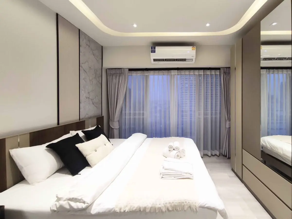 Luxurious modern bedroom with elegant decor and large windows.
