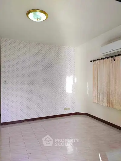 Spacious empty room with tiled floor and air conditioning, ready for customization.