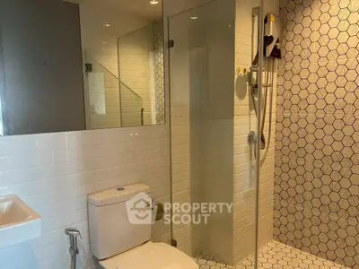 Modern bathroom with geometric tile design and glass shower enclosure