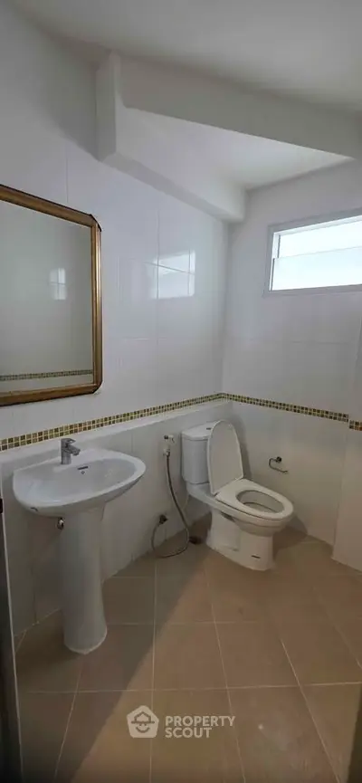 Modern bathroom with pedestal sink and toilet in a bright, tiled space.