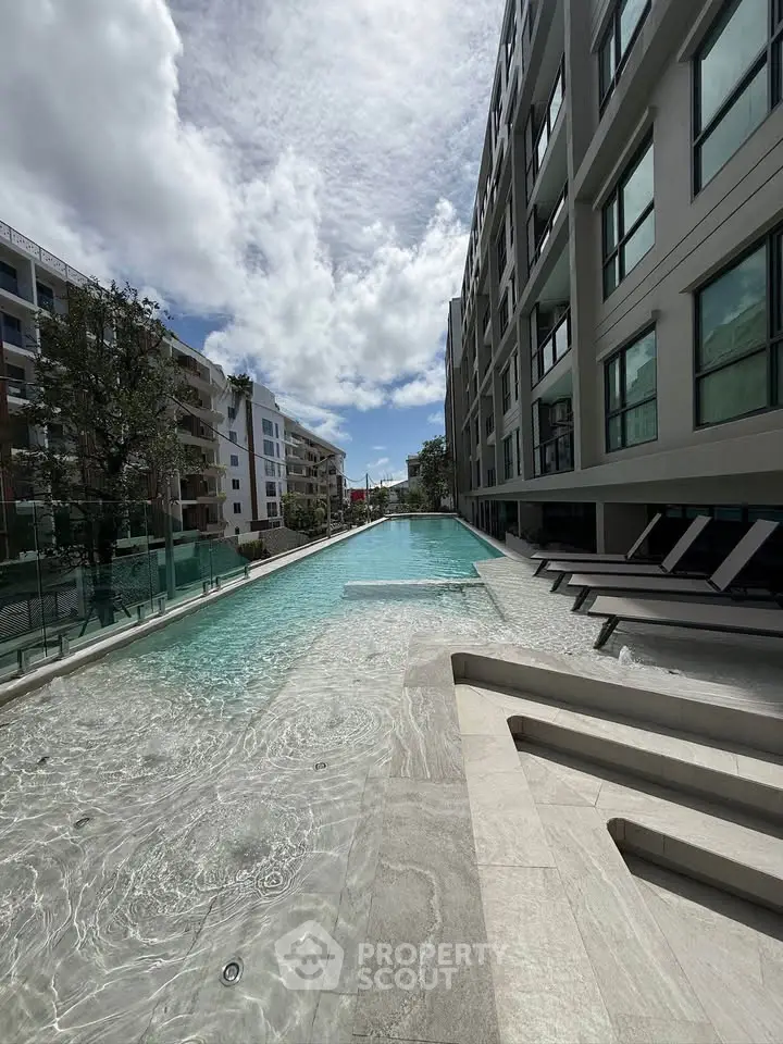 Luxurious modern apartment complex with stunning outdoor pool and sun loungers.
