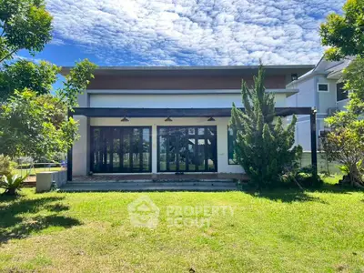 Modern house exterior with lush green lawn and clear blue sky, showcasing contemporary architecture.