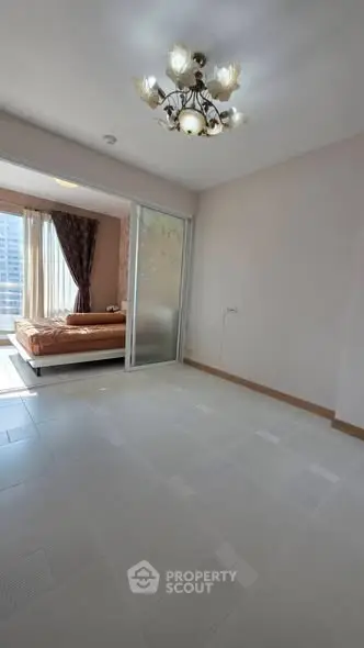 Spacious bedroom with elegant chandelier and large windows for natural light.