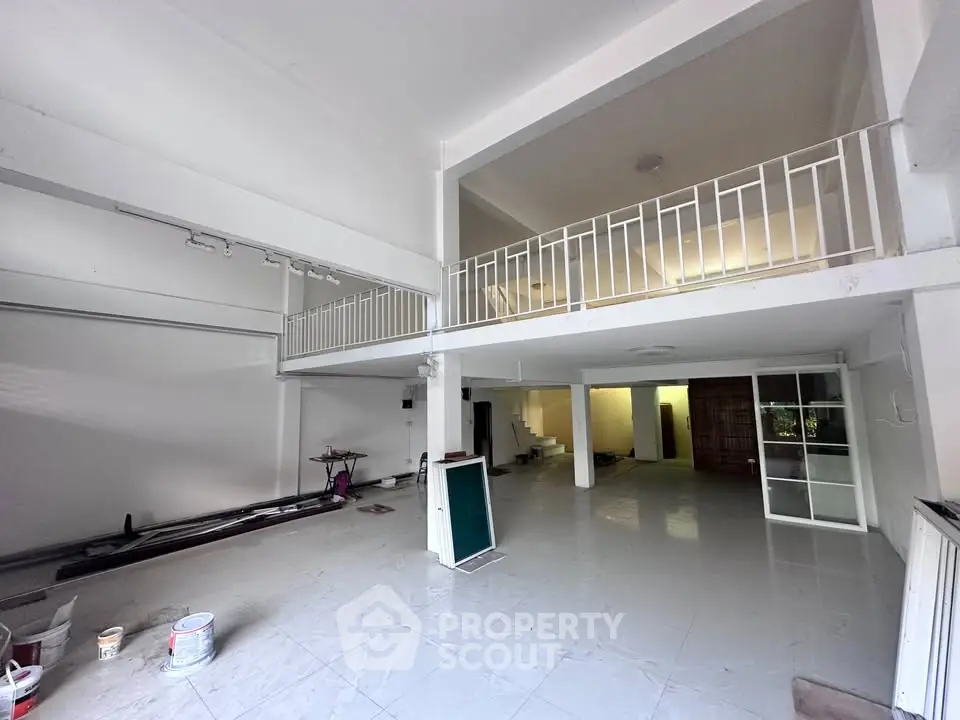 Spacious two-level interior with high ceilings and white walls, ideal for creative workspace or studio.