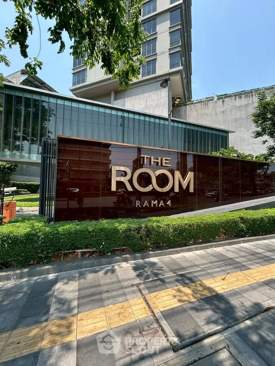 Modern condominium building exterior with sleek design and lush greenery at The Room Rama.