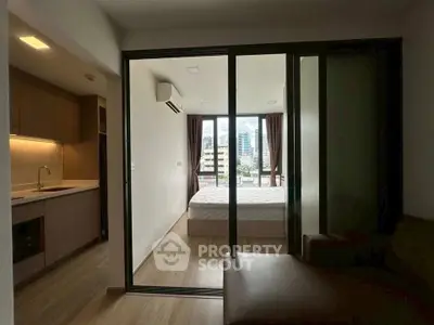 Modern apartment interior with open kitchen and cozy bedroom featuring city view.