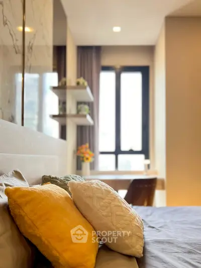 Cozy bedroom with stylish decor and natural light from large window.