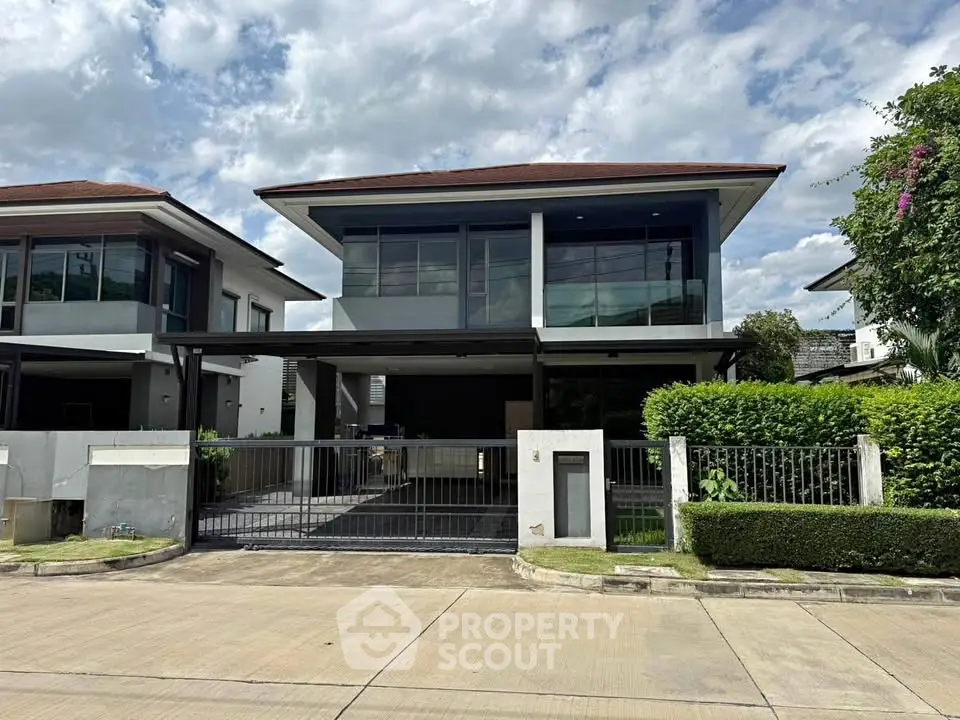 Modern two-story house with large windows and gated driveway in a suburban neighborhood.