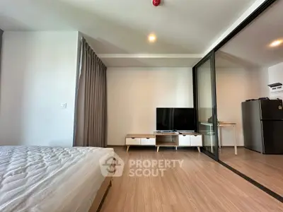 Modern bedroom with TV and glass partition, featuring minimalist design and wooden flooring.