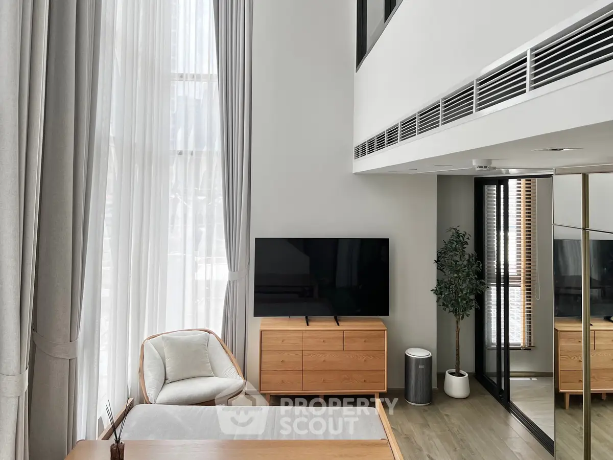 Modern living room with high ceilings, large windows, and stylish furniture
