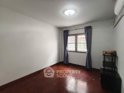 Spacious empty room with wooden flooring and window, ideal for customization.