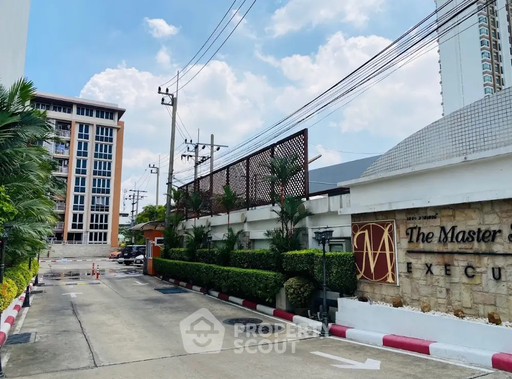 Modern condominium entrance with lush greenery and clear blue sky