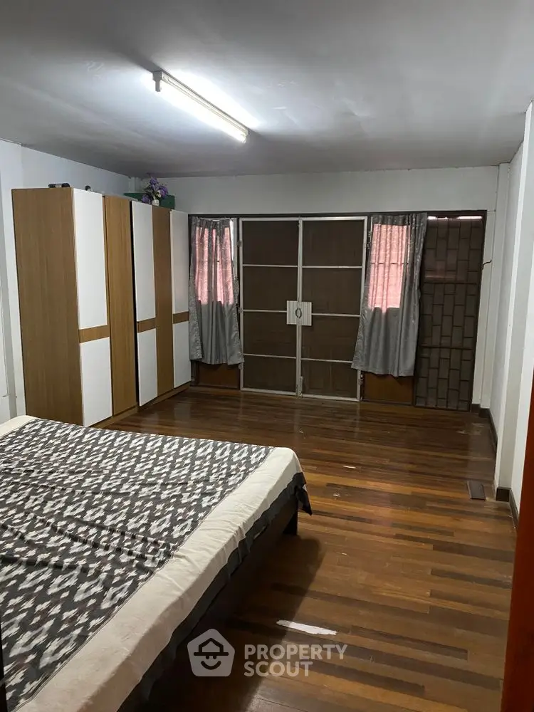 Spacious bedroom with wooden flooring and ample natural light