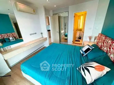 Modern bedroom with teal accents and ensuite bathroom in stylish apartment.