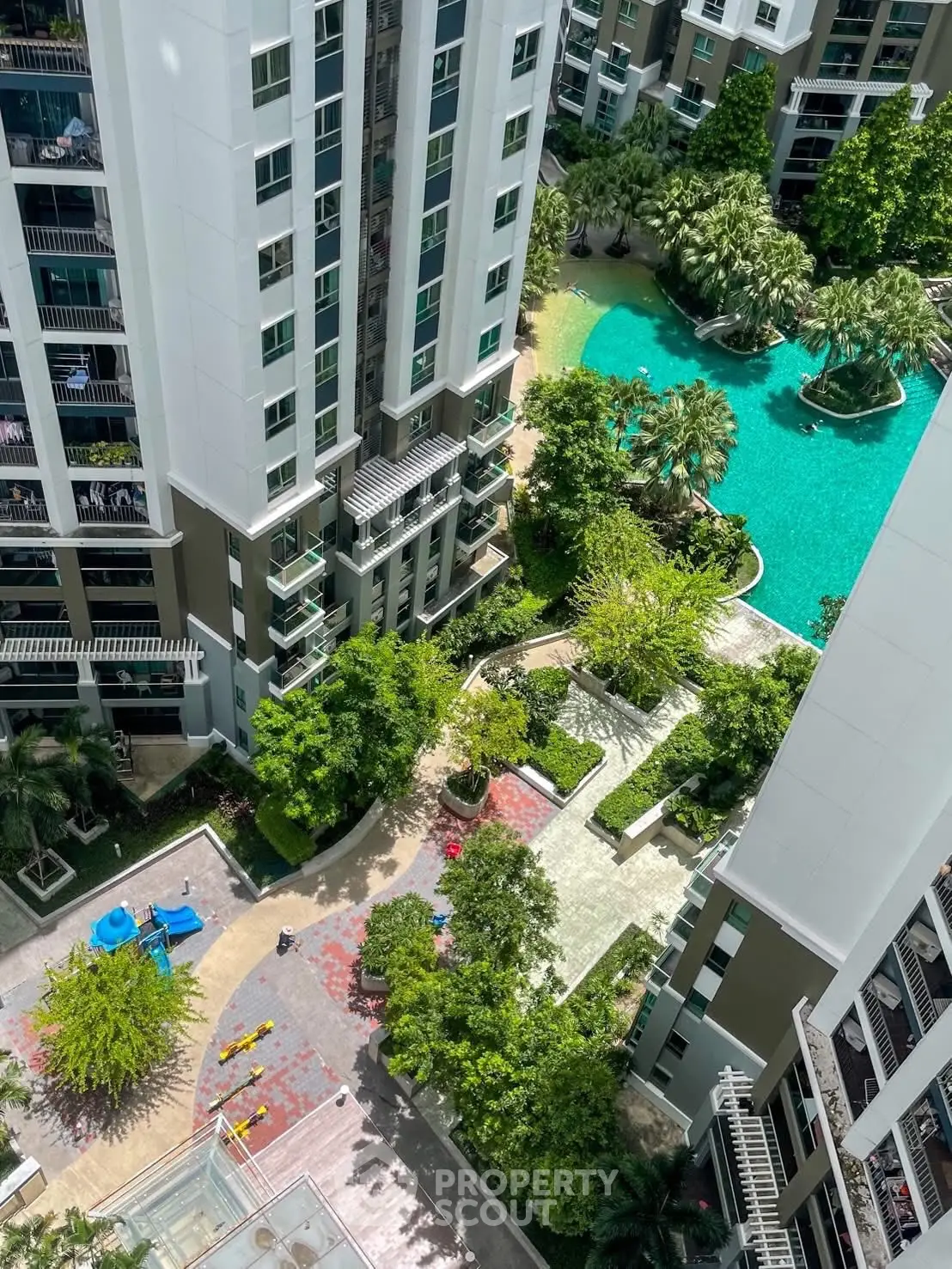 Stunning aerial view of modern residential complex with lush gardens and inviting pool area.