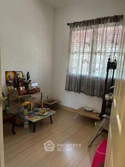 Cozy small room with wooden floor and decorative items, perfect for meditation or study.