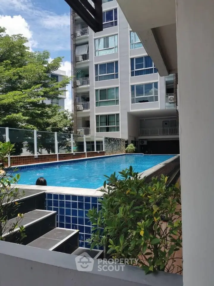Modern apartment building with a luxurious outdoor pool and lush greenery.