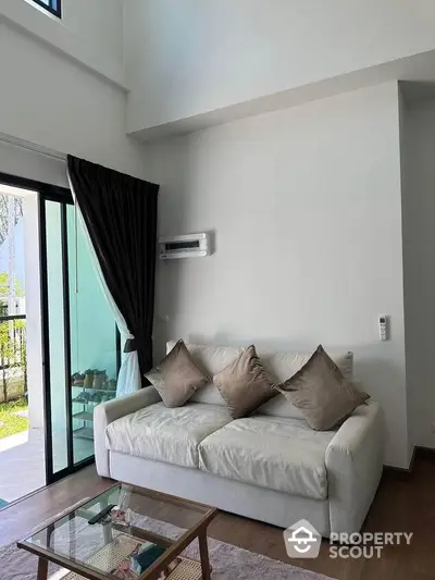 Modern living room with cozy sofa and glass coffee table near balcony