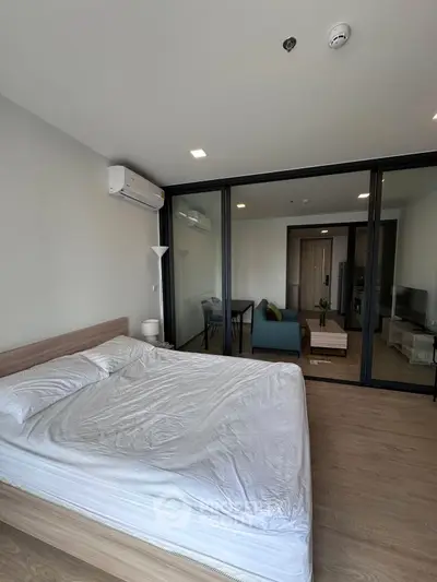 Modern bedroom with wooden flooring and glass partition leading to living area.