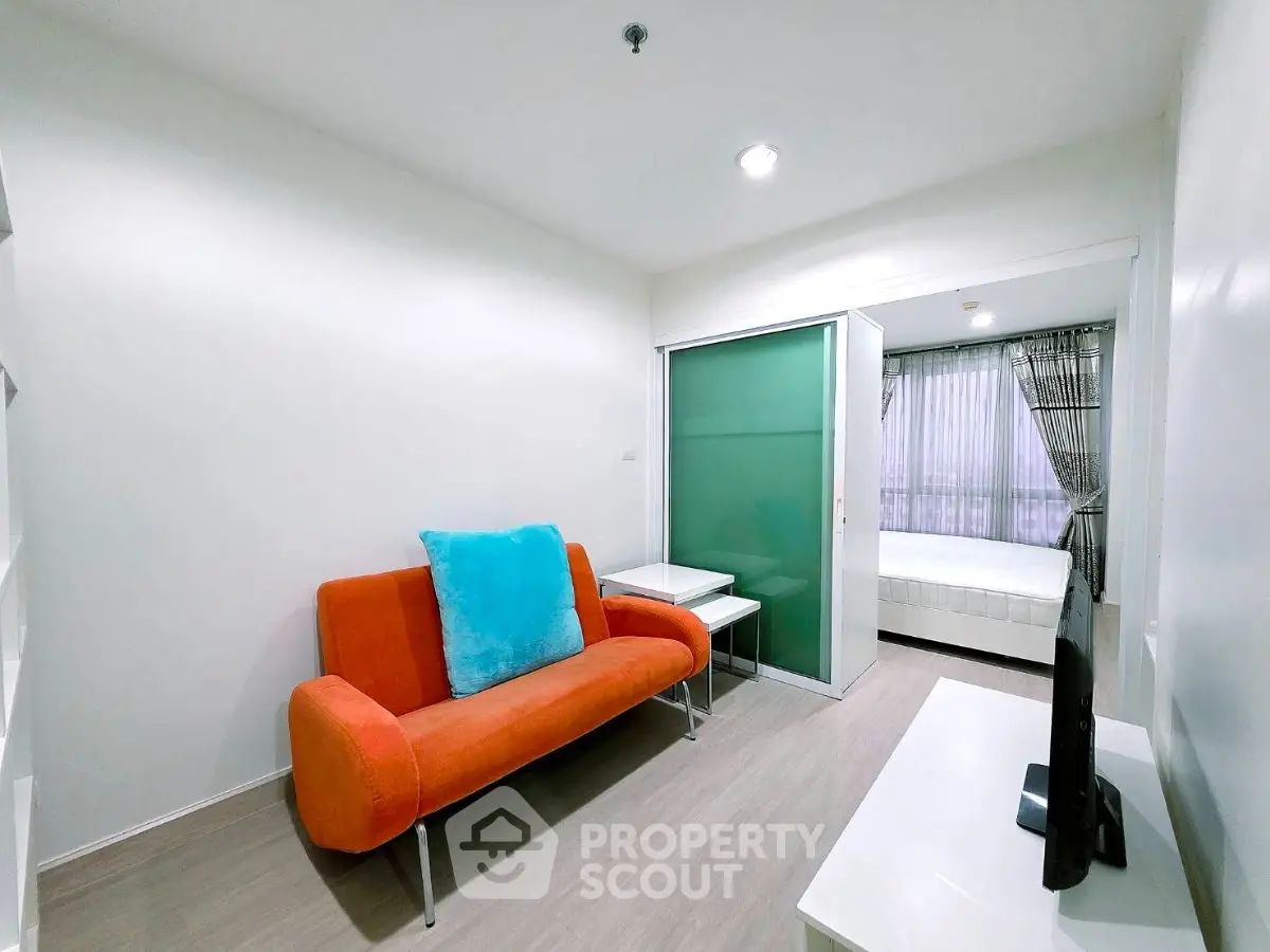 Modern apartment with vibrant orange sofa and sleek sliding door to bedroom