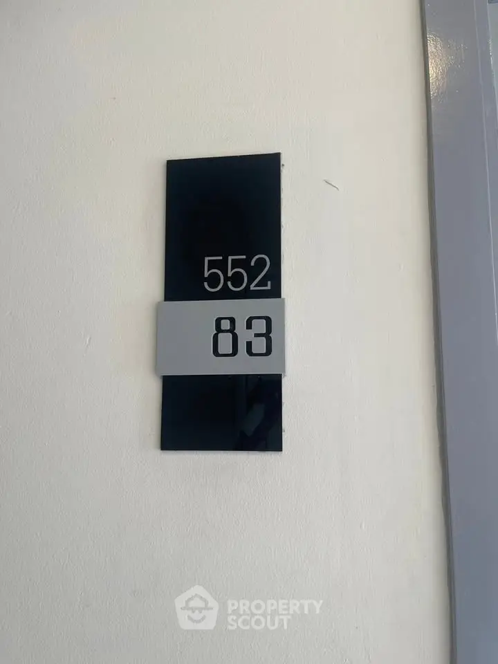 Modern apartment door number 552 83 on sleek black and gray plaque.