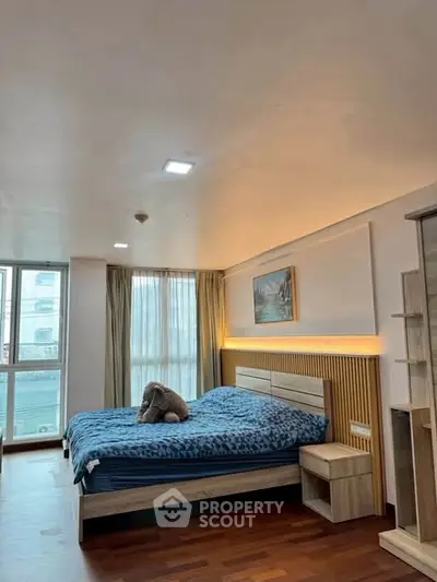 Spacious bedroom with modern decor and large windows offering natural light.