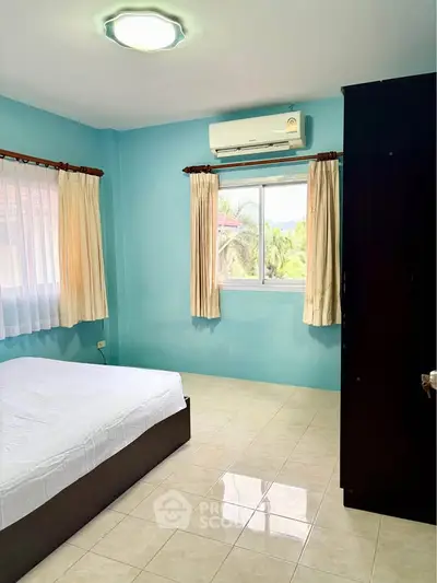Spacious bedroom with natural light and air conditioning in a serene setting.