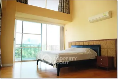 Spacious bedroom with large windows and balcony access in modern apartment.
