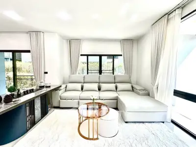 Luxurious modern living room with elegant white sofa and stylish decor, featuring large windows for natural light.