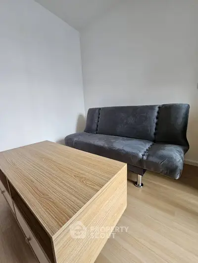 Modern minimalist living room with sleek gray sofa and wooden coffee table.