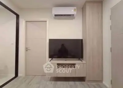 Modern living room with sleek TV setup and air conditioning, featuring minimalist design and neutral tones.