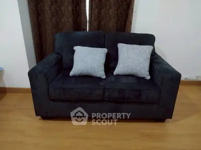 Cozy dark sofa with decorative pillows in a modern living room setting.