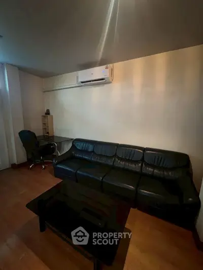 Cozy living room with black leather sofa and air conditioning