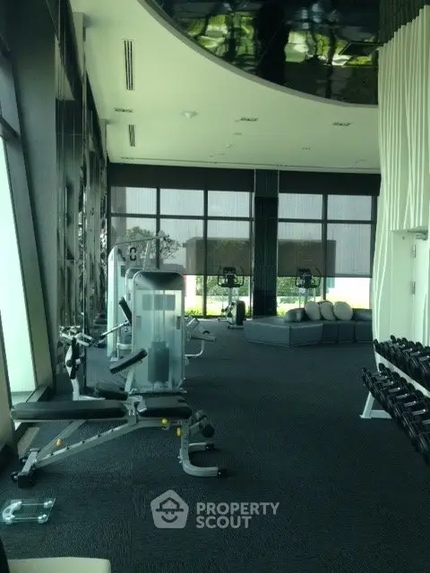 Luxurious gym with modern equipment and floor-to-ceiling windows in upscale residential building.