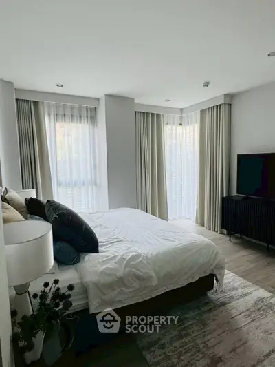 Elegant bedroom with large windows and modern decor, perfect for relaxation and comfort.