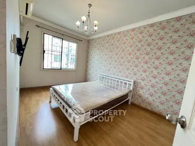 Charming bedroom with floral wallpaper and elegant chandelier in cozy apartment.