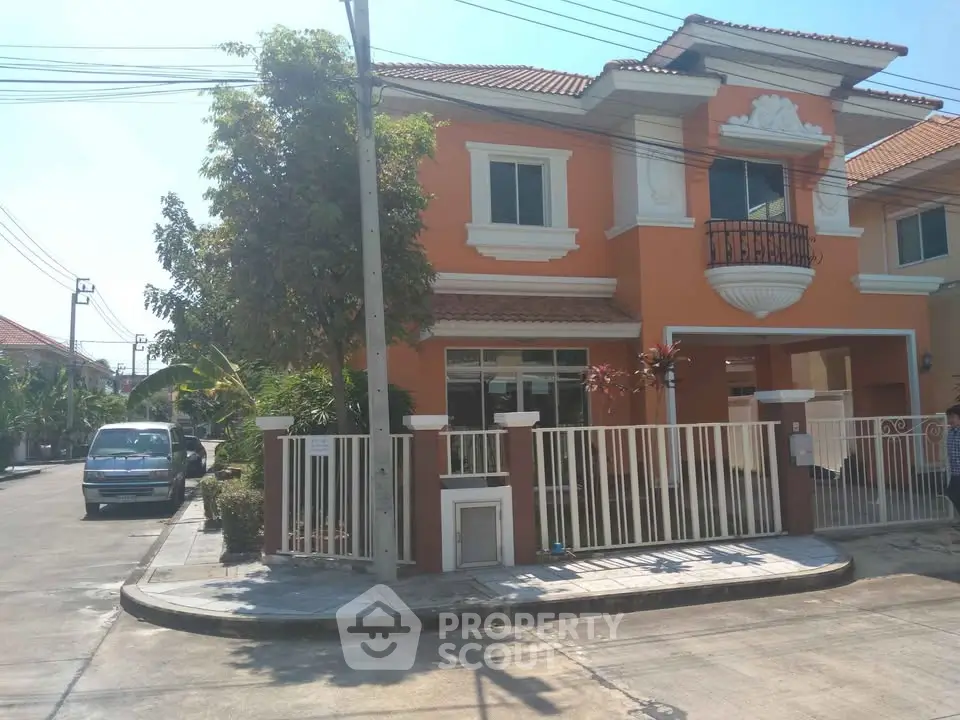 Charming two-story orange house with balcony and gated front yard in a suburban neighborhood.
