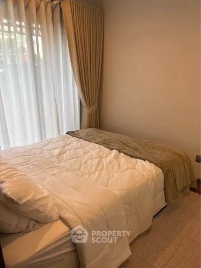 Cozy bedroom with elegant curtains and soft bedding, perfect for relaxation.