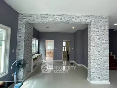 Spacious modern living room with stylish stone accent wall and large windows for natural light.