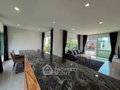 Spacious modern living room with marble countertop and large windows offering garden views.