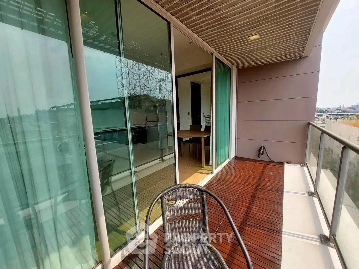 Spacious balcony with wooden flooring and glass railing in modern apartment