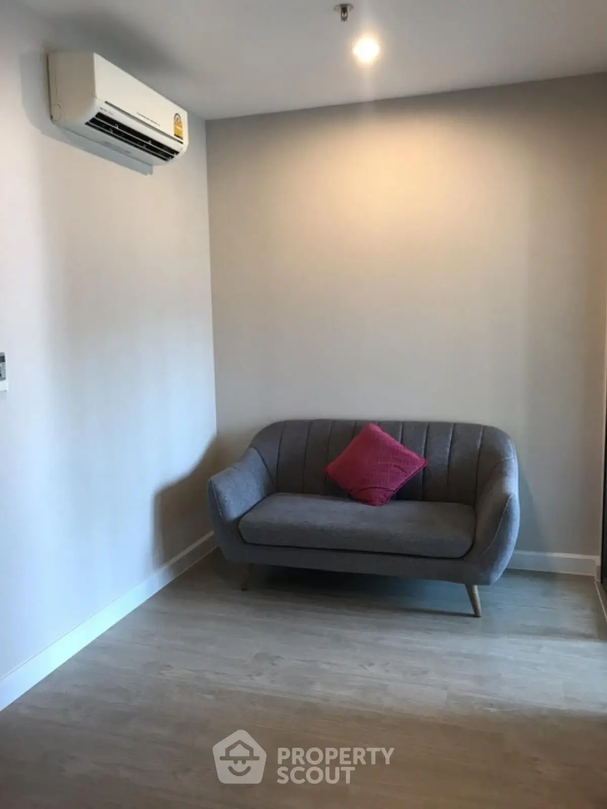 Cozy minimalist living room with modern sofa and air conditioning.