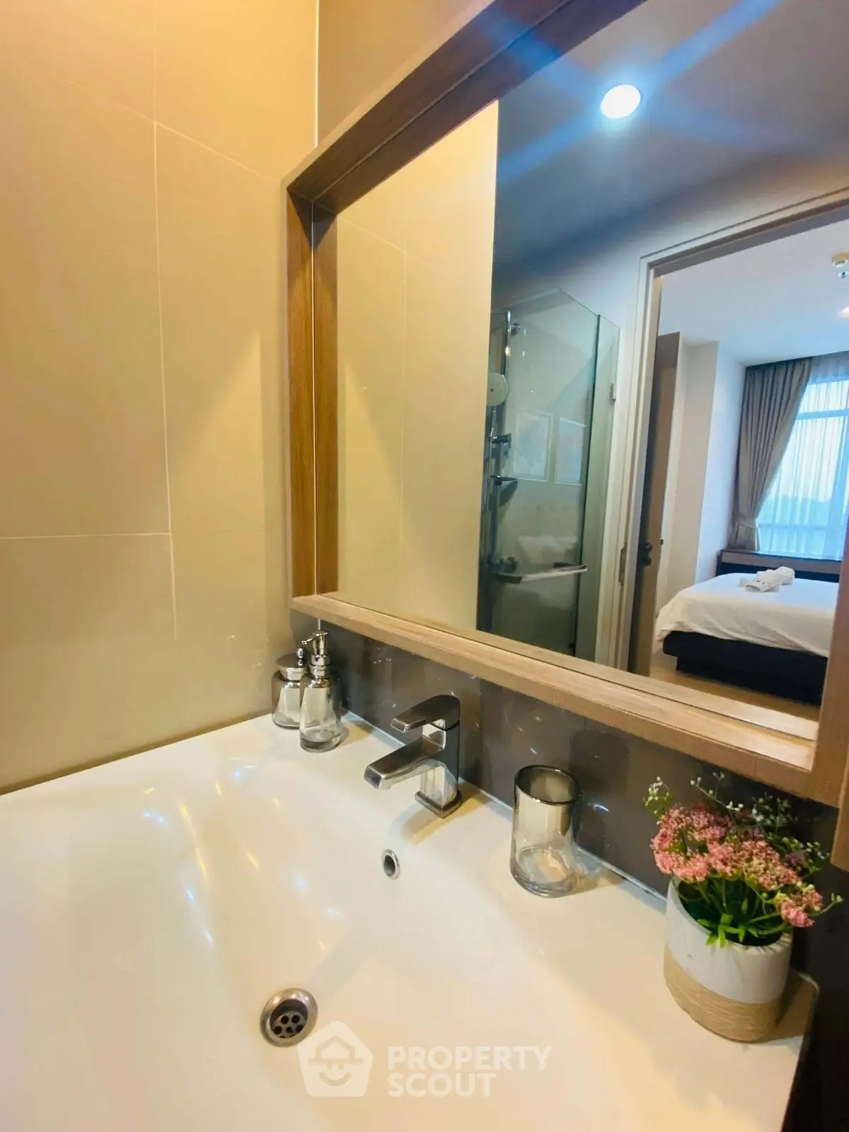 Modern bathroom with sleek sink and mirror, view into cozy bedroom with natural light.