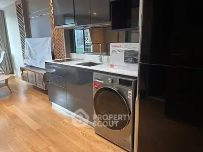 Modern kitchen with sleek cabinetry and built-in washing machine in stylish apartment.